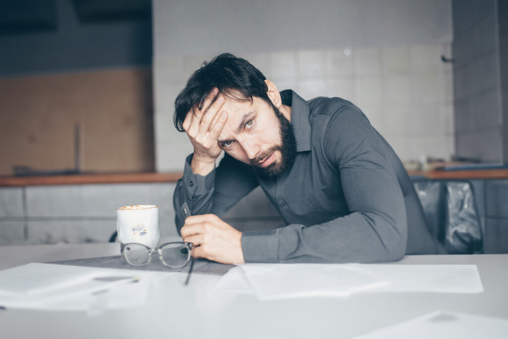A stressed out man slouched over a table